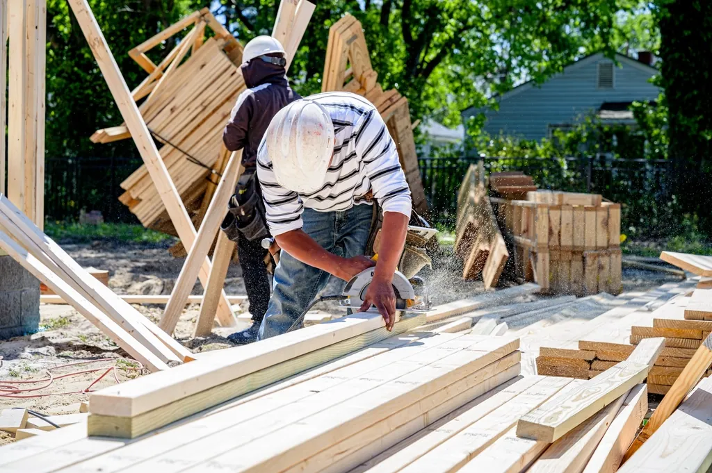 Carpenter cutting lumber outdoors on a job site